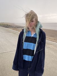 Girl standing in rain and wind on seafront