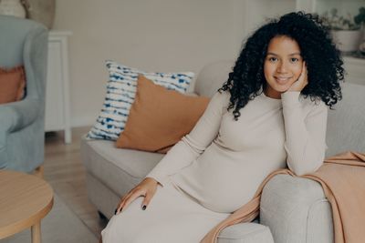 Portrait of smiling woman sitting on sofa at home
