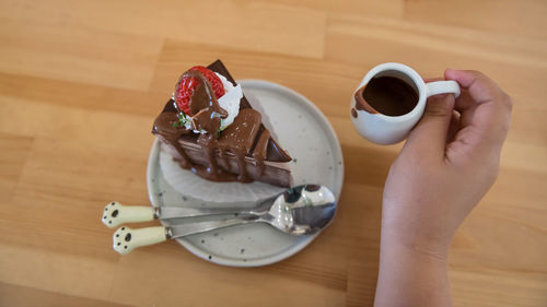 Cropped hand of woman holding coffee on table