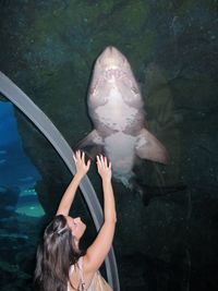 Side view of mid adult woman looking at fish in aquarium