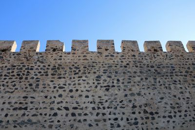 Low angle view of fortified wall against clear blue sky