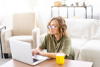 Young woman using mobile phone while sitting on sofa