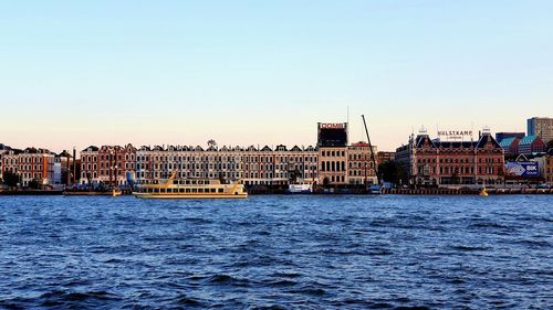 View of buildings by river against clear sky