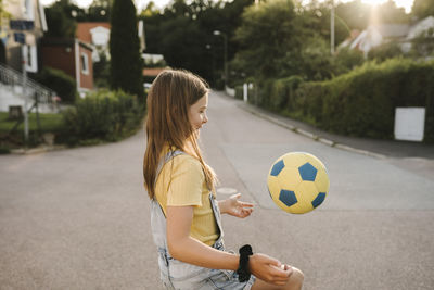 Woman playing soccer ball in city