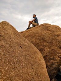 Low angle view of man sitting on rock