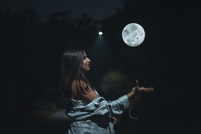 Side view of woman standing against black sky