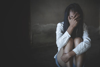 Woman sitting on wall at home