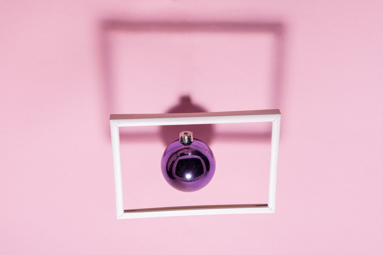 CLOSE-UP OF DIGITAL CAMERA AGAINST WALL WITH PINK BACKGROUND