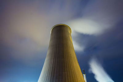 Low angle view of smoke stack emitting air pollution against sky at night