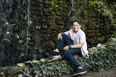 Portrait of smiling young woman sitting on rock