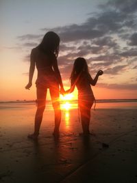 Friends enjoying at beach during sunset