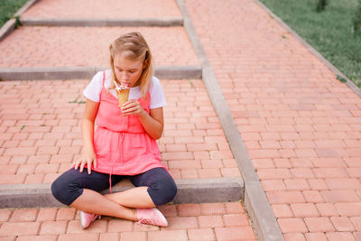 Full length of woman sitting on footpath