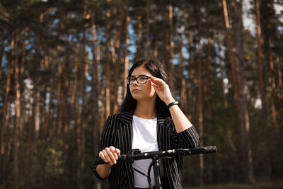 Low angle view of woman wearing eyeglasses standing against trees