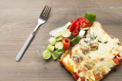 Italian food known as lasagna on a glass plate and a wooden background.