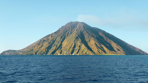 Scenic view of sea and mountains against clear blue sky