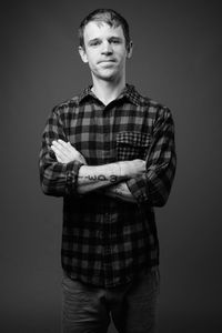 Portrait of young man standing against gray background