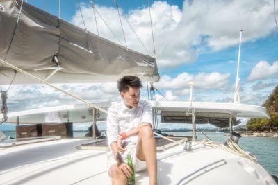 Man holding sailboat in sea against sky