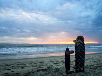 Skateboard on beach against sky during sunset