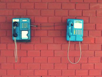 Blue pay phones on brick wall