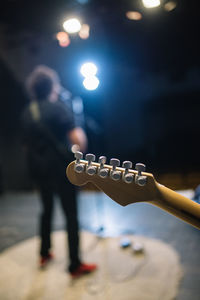 Back view and closeup of guitar headstock on stage.