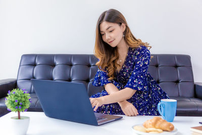 Young woman using phone while sitting on table