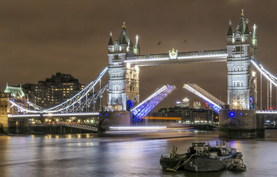 Illuminated bridge over river at night