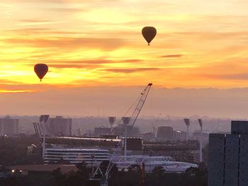 Hot air balloons in city against orange sky