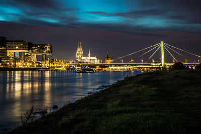 Illuminated bridge over river in city at night