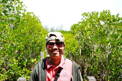 Portrait of smiling man wearing sunglasses against trees