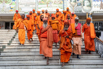 Rear view of people standing against orange wall