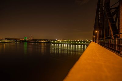 Illuminated bridge over river against sky at night