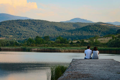 Rear view of people looking at lake against mountains