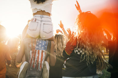 Man carrying friend on shoulder while enjoying in crowd at music event