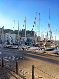 Sailboats moored on harbor against clear blue sky