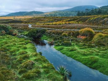 Scenic view of river by mountains against sky