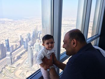 Happy father with baby boy by window in building