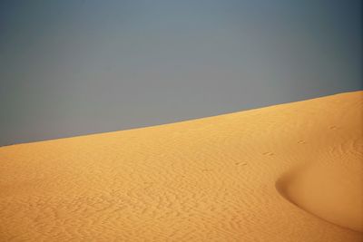 Sand dunes in desert against clear sky