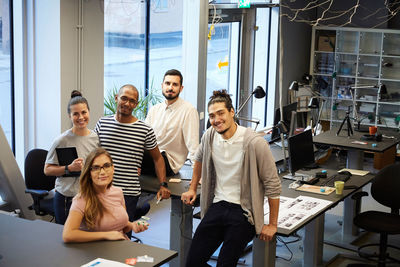 Portrait of confident male and female entrepreneurs at desk in creative office