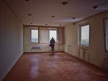 Full length rear view of woman standing in abandoned room