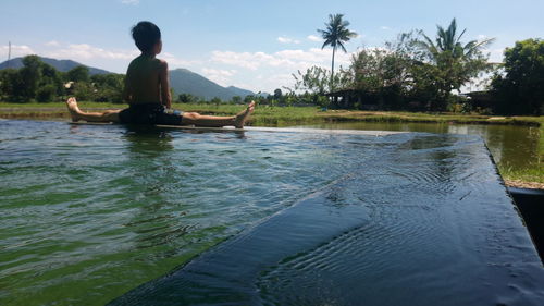 Man sitting on boat in lake against sky