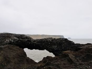 Scenic view of sea and cliff against clear sky