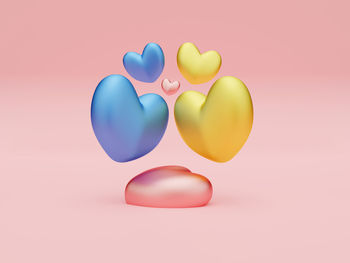 Close-up of multi colored balloons against pink background