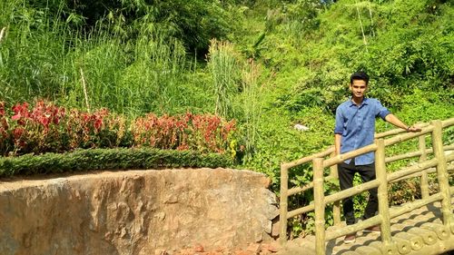 Young man standing against plants