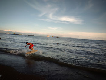 Man surfing in sea against sky