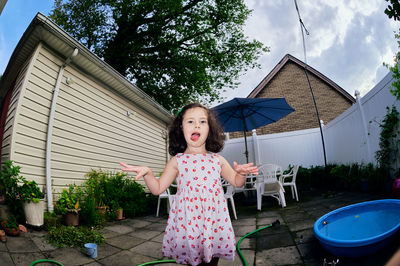 Cute young girl in a summer dress playing in a suburban backyarrd