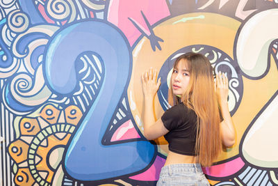 Full length of woman standing against graffiti wall