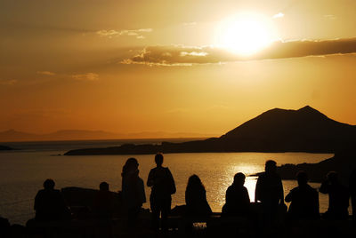 Silhouette people on beach against sky during sunset