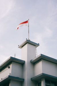 Low angle view of flags on building against sky