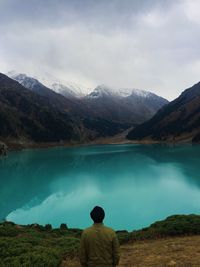 Rear view of man looking at lake against mountain