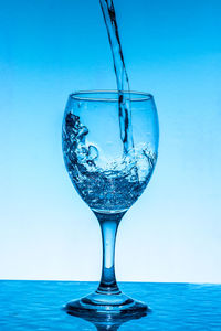 Close-up of glass of water against blue background